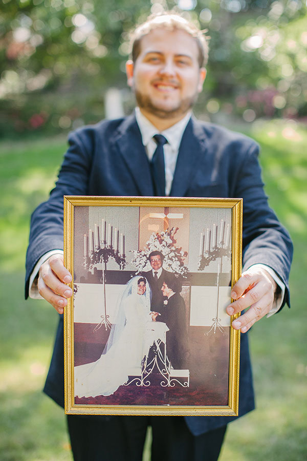 groom holding parents wedding photo