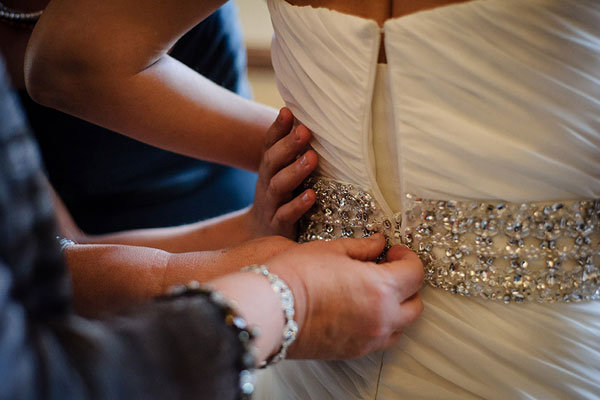 bride putting on wedding gown 