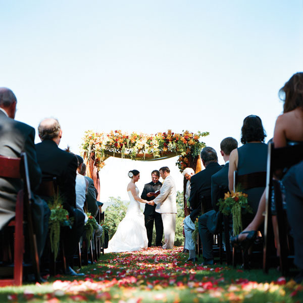 summer wedding ceremony The couple exchanged vows under a frame draped with 