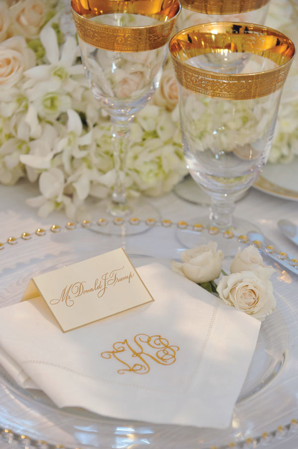 Topping each setting baby roses and a white linen napkin embroidered in