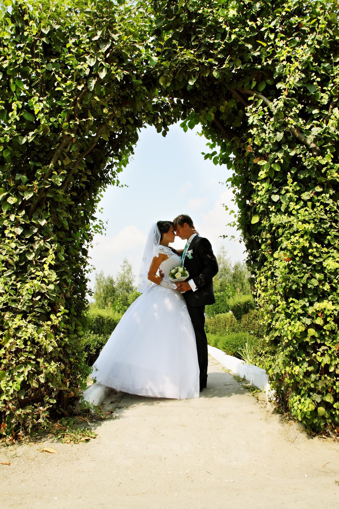 bride and groom under wedding arch