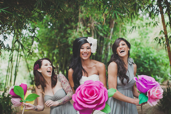 bride and bridesmaid holding giant paper flowers 