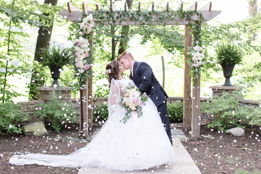 Flower petals bride and groom kiss