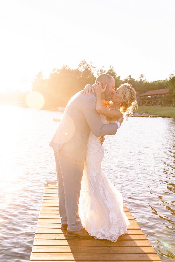 Bride and groom kissing on a lake dock