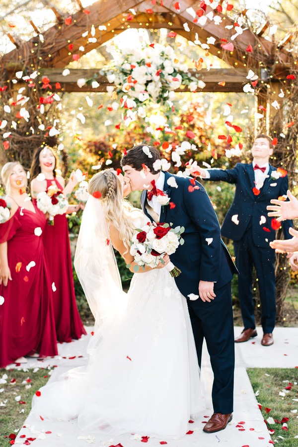 bride and groom kissing under flower petals