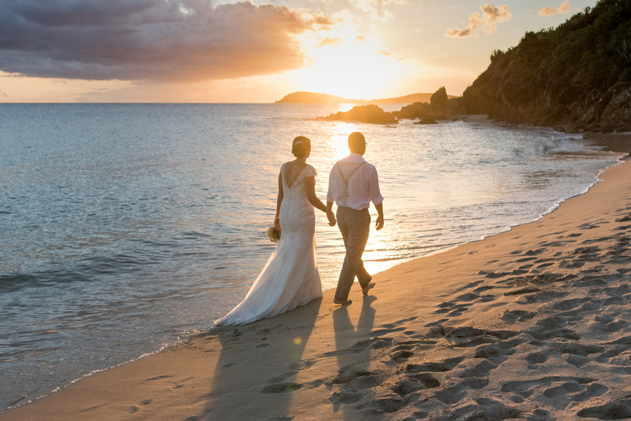 Bride and groom walking on the beach at sunset