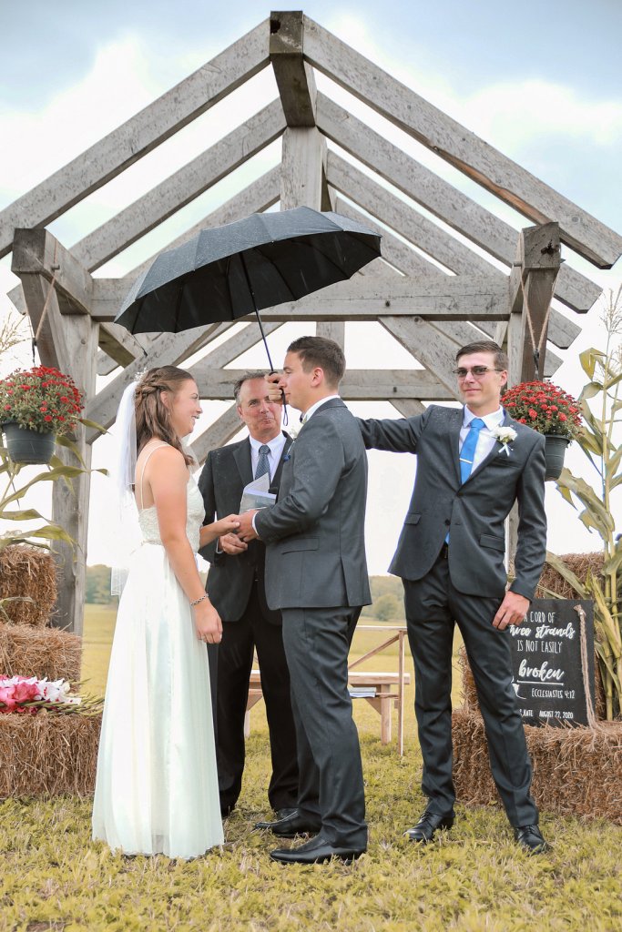 best man holding umbrella at wedding ceremony
