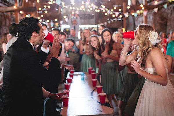 Bride and groom playing flip cup at wedding