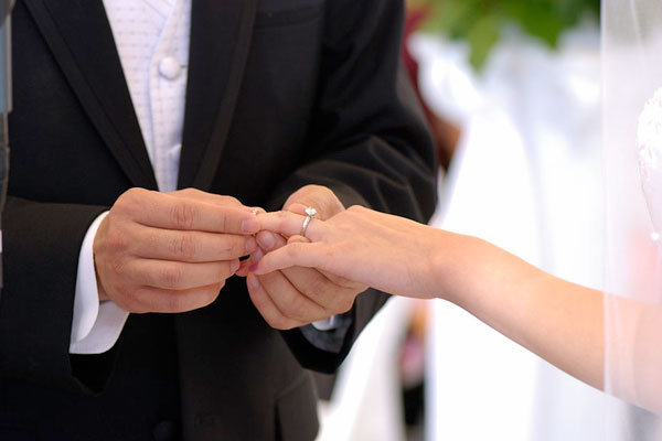 groom puttimg wedding band on bride's finger 