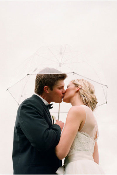 bride and groom under a clear umbrella