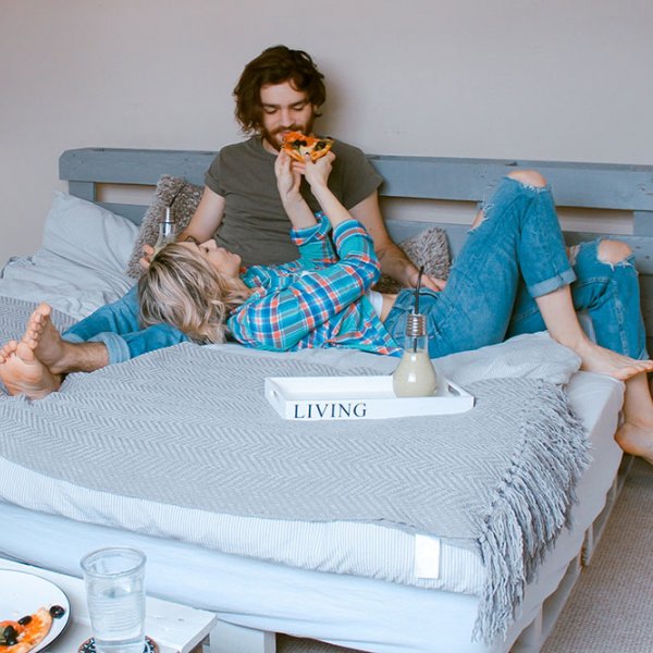 Happy couple eating pizza in bed