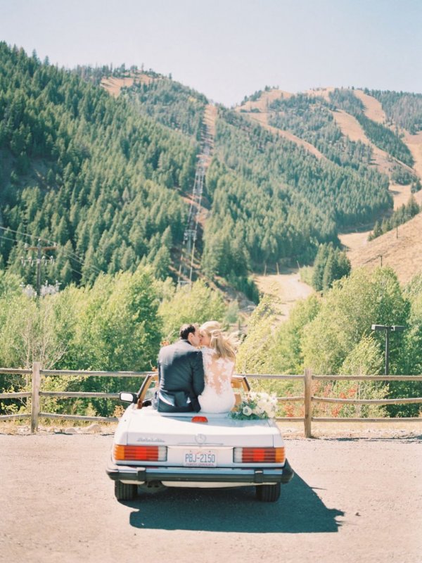 Bride and Groom sitting on car