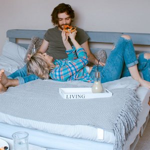 Happy couple eating pizza in bed